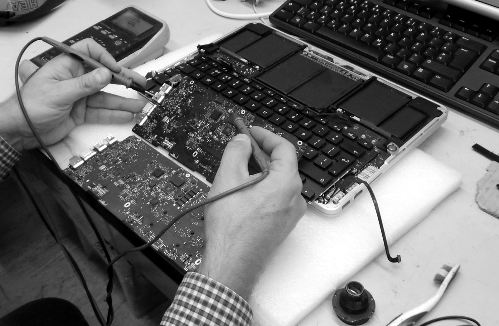 Un technicien Creative IT contrôle la carte mère d'un MacBook Pro au multimètre